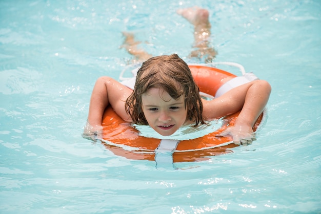 夏の週末のプールリゾートのスミリングボーイ、アクアパークの子供がプールの夏のウォーターアクティビティで泳いでいます...