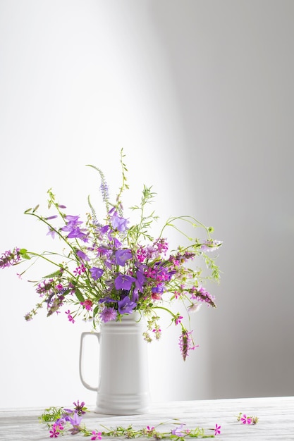 Summer wild flowers in white jug on white background