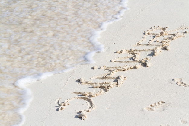 Summer written on the beach with wave.