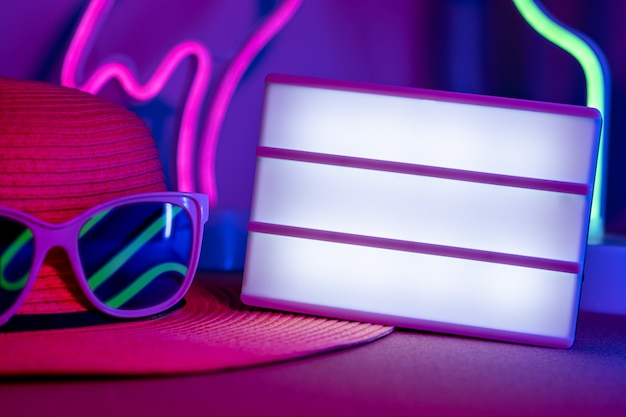 Summerblank light box on hat with sunglasses refection neon pink and blue and green light on table