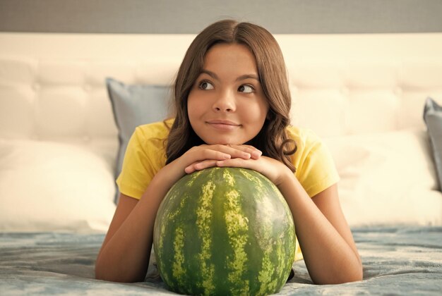 Summertime cheerful child hold water melon watermelon at home kid with fruit