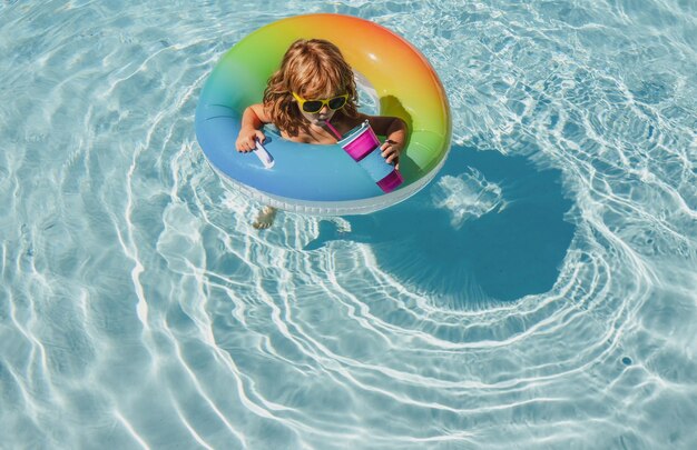 Summertime cool boy with swimming ring and sunglasses. summer\
kids weekend or vacation. funny happy child boy in pool on\
inflatable rubber circle ring.