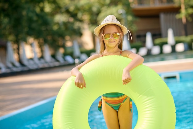 夏時間。スイミングプールで黄色いチューブを持つかわいい小さな女の子