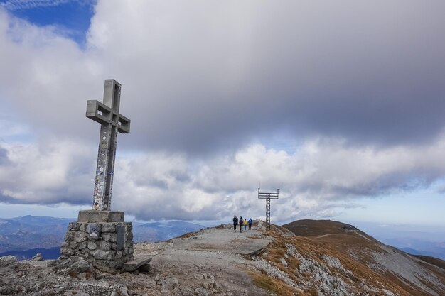 Summit cross with hikers on the highest mountain of lower austria with amazing view