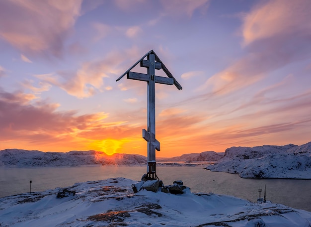 Teriberka, 러시아에서 일출 눈 덮인 산 꼭대기에 산과 정통 십자가에 태양 천사