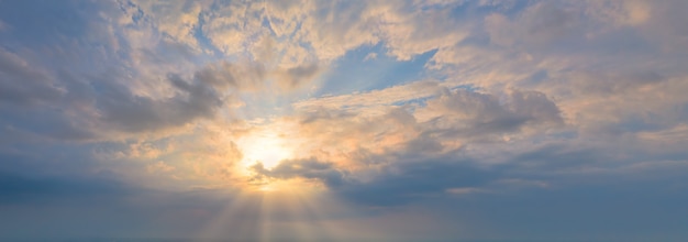 The sun in the blue sky with clouds rays shine through the clouds panoramic shot