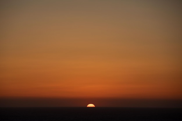 海の地平線の太陽の円盤カラフルな夕日のコピースペース