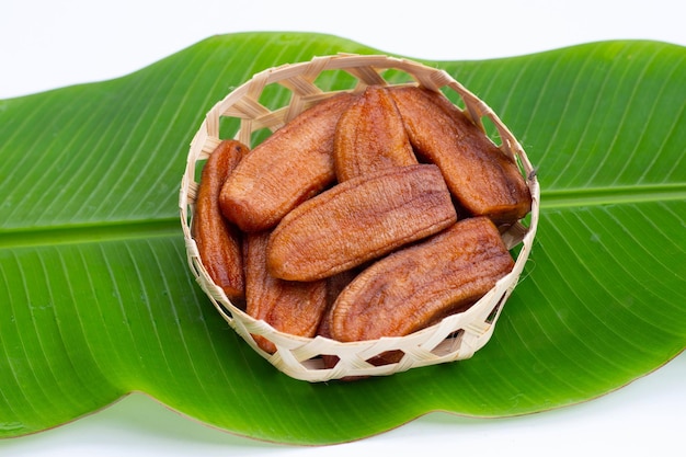 Sun dried bananas in bamboo basket on green leaf