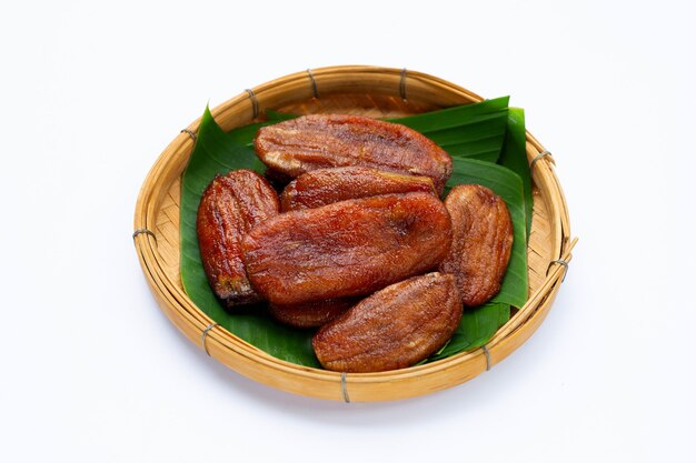 Sun dried bananas in bamboo basket on white surface