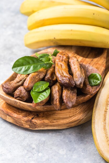 Sun dried bananas in wooden bowl on stone background