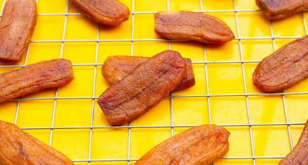 Sun dried bananas on yellow background.