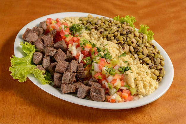 Sun dried meat with beans manioc flour and vinaigrette Traditional snack served in Brazilian restaurants