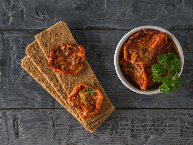 Sun-dried tomatoes and toasted bread on a wooden table. The view from the top