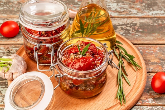 新鮮なハーブとスパイス、ガラスの瓶にオリーブオイルを入れたサンドライトマト。バナー形式。