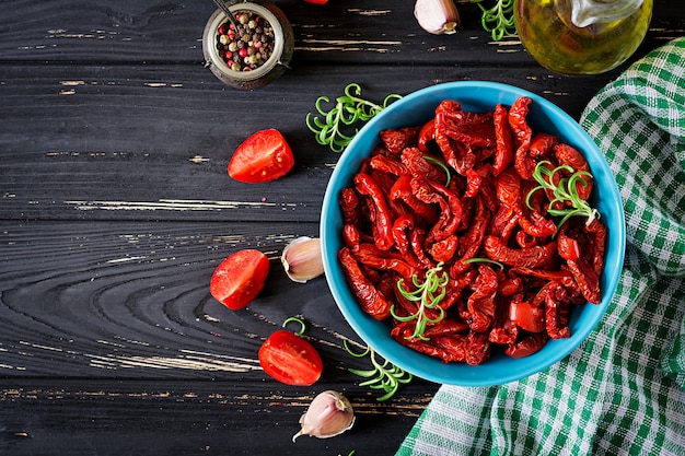 Sun dried tomatoes with herbs and garlic in  bowl on wooden table. Italian food. 