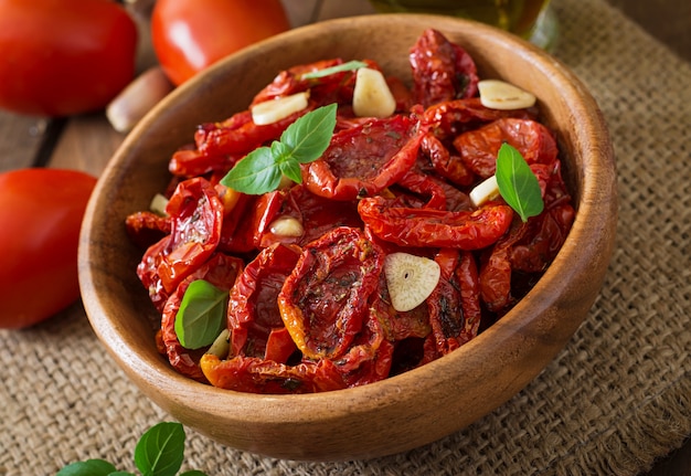 Sun-dried tomatoes with herbs and garlic in wooden bowl