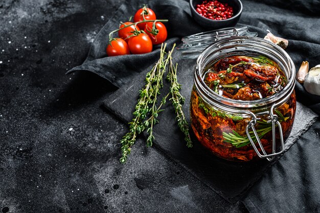 Sun dried tomatoes with herbs and salt in olive oil in a glass. Top view. Copy space