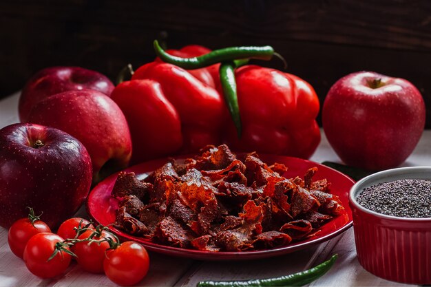 Sun-dried tomatoes with paprikas and chilly peppers on red plate