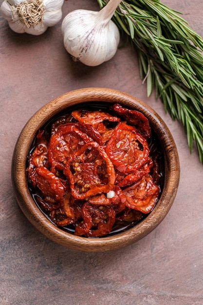 Sun dried tomatoes in wooden bowl Dried tomatoes with olive oil rosemary salt herbs and garlic