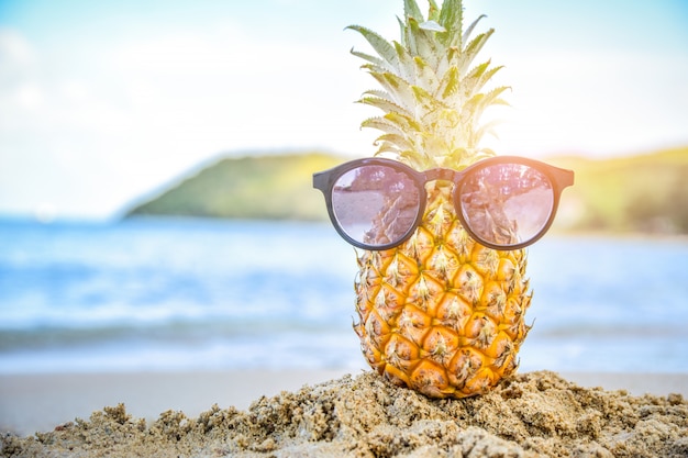 Sun glass is on pineapple at beach sea view background,Summer holiday concept