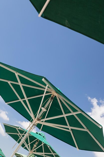 Sun green open umbrella comfortable rest by the ocean with personal beach parasol on beautiful cote dazur coastline safe tan accessory sunstroke protectionSummer concept vacation