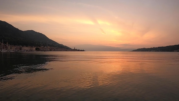 The sun is setting over lake garda.