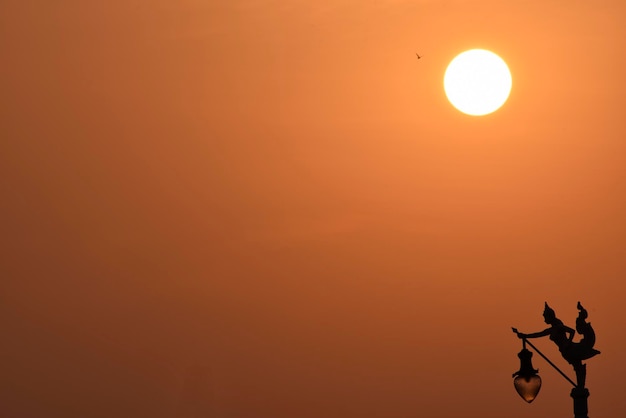 Sun is shining over an angel electricity post silhouette in sunset time