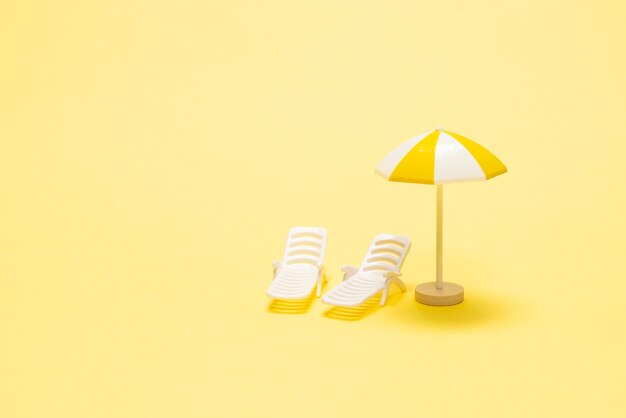 Sun lounger and yellow umbrella on a yellow.