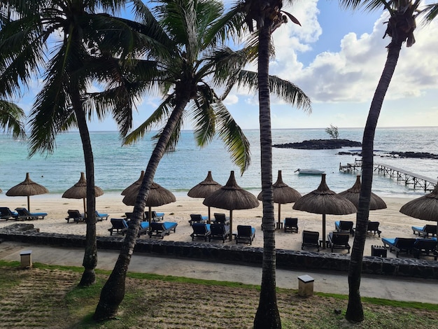 Sun loungers on pier in front of a tropical island by sea and ocean