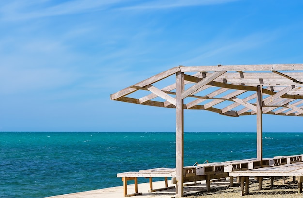 Sun loungers and a wooden shed on the old pier by the sea. Bright blue sky and calm sea, sea view vacation. The beginning of the summer season on the Black Sea coast