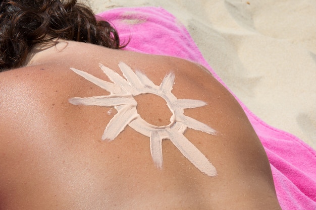 Солнце сделано с солнцезащитным кремом на спине женщины