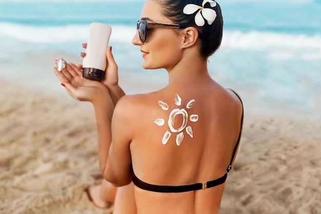 Protezione solarecrema solare bellezza donna che applica crema solare sulla spalla abbronzata a forma di pelle solare a