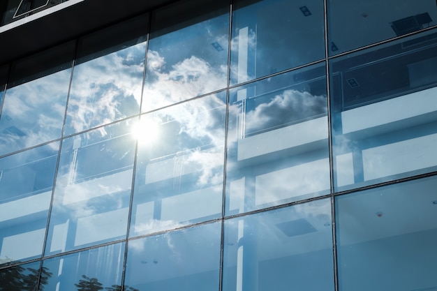 Foto riflessione del raggio di sole e del cielo blu sull'edificio per uffici della finestra