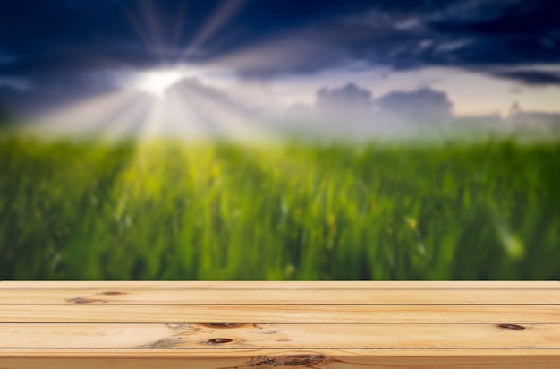 sun rays on green paddy farm background with wooden table product display