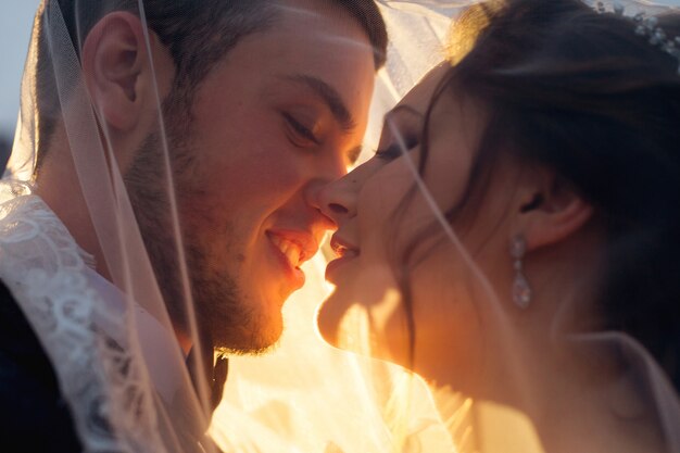 Sun rays shine on newlyweds who want to kiss under the wedding veil