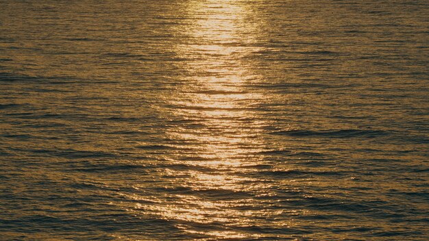해가 지는 해수 배경에서 해수 표면에 대한 태양 반사와 파동
