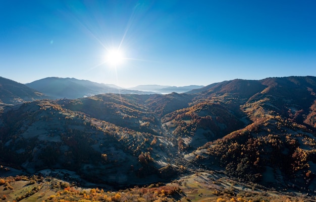 黄ばんだ木々のある高い山頂から昇る朝日