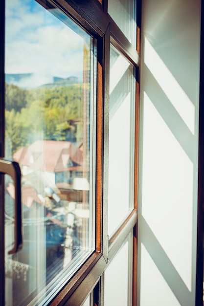 Sun shines through the modern window in the morning. Background of forest and mountains