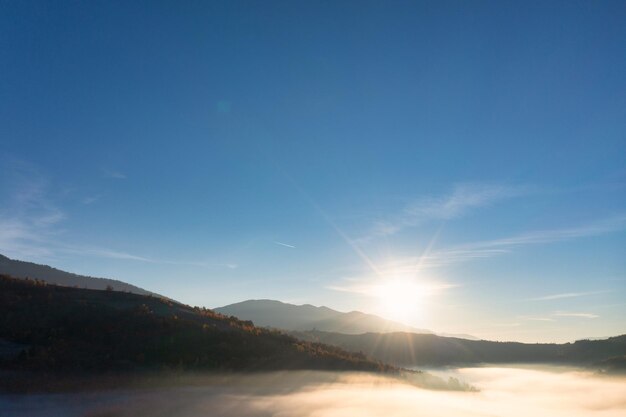 Sun shining above layer of white fluffy clouds at sunset