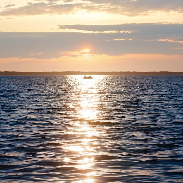 Sun track and fishing boat on lake surface