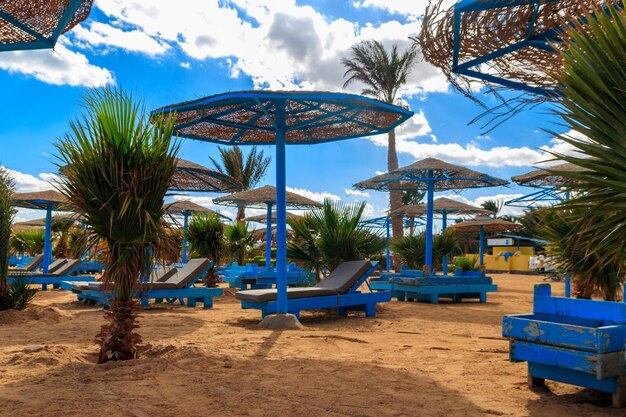 Sun umbrellas and chaise lounges on tropical beach. Concept of rest, relaxation, holidays, resort