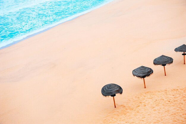 Sun umbrellas on the sandy beach. Top view. Beautiful coast of Atlantic ocean in Algarve, Portugal. Summer travel background.