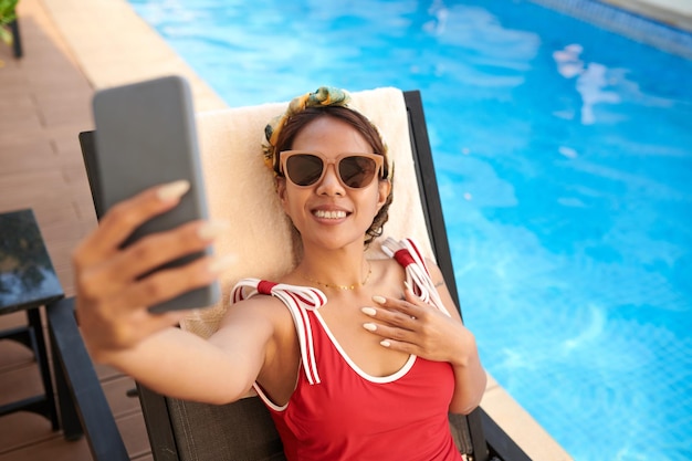 Sunbathing woman taking selfie for blog