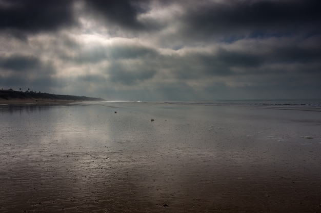 写真 カディスのビーチで嵐の雲を突破する太陽光線