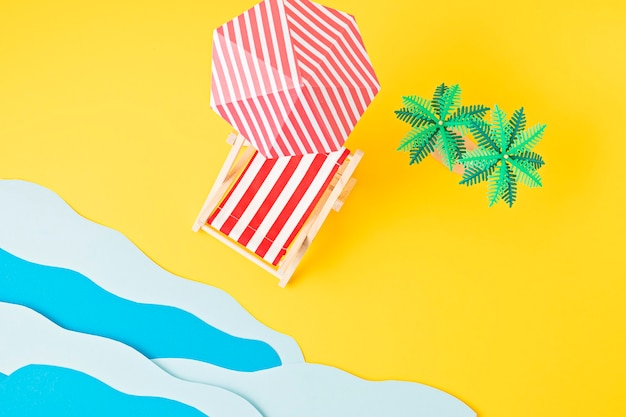 Lettino, palme giocattolo, onde del mare di carta. vacanze estive e spiaggia, concetto di vacanze al mare