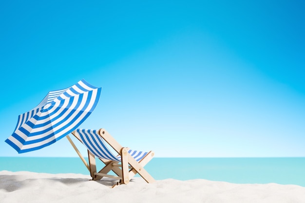 Foto lettino sotto l'ombrellone sulla spiaggia di sabbia in riva al mare