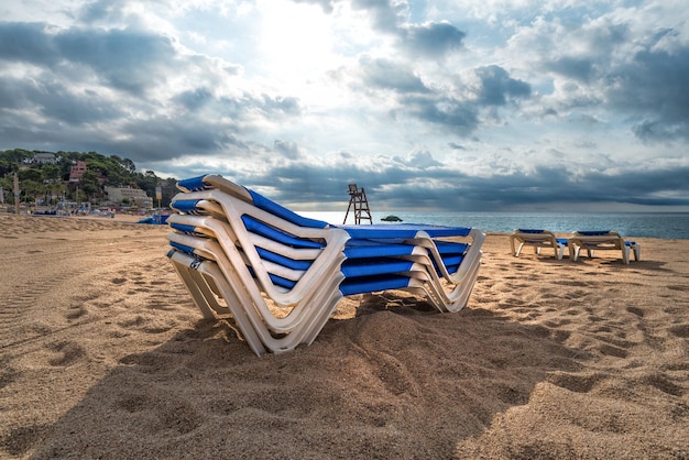 Sunbeds collected in a pile in rainy weather in Lloret de Mar, Spain