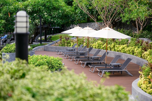 Sunbeds with parasol on wooden patio at poolside in garden