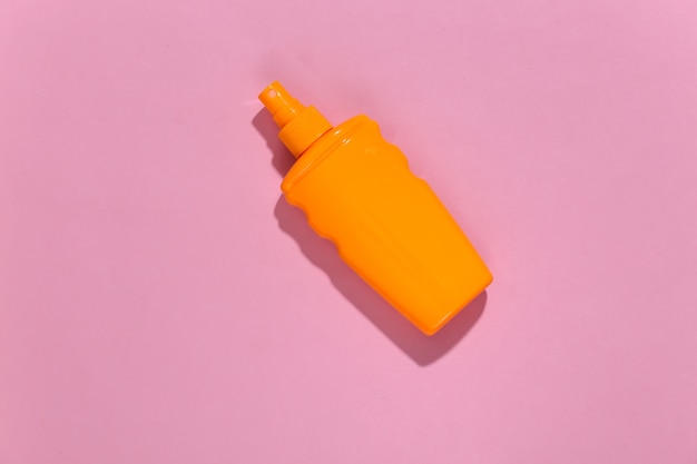 Sunblock bottle on pink bright sunny. Skin protection. Beach vacation.