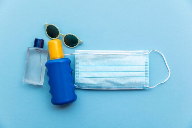 Suncream and sanitiser bottle on a protective medical face mask covid summer